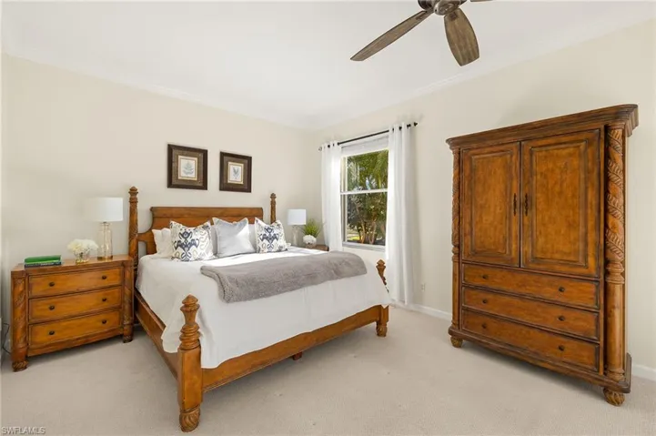 Bedroom featuring light carpet, ornamental molding, and a ceiling fan