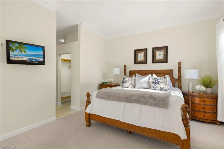 Bedroom featuring ornamental molding, light colored carpet, and a spacious closet