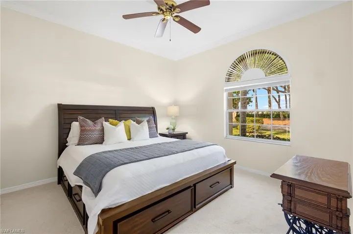 Bedroom with ornamental molding, light carpet, and ceiling fan