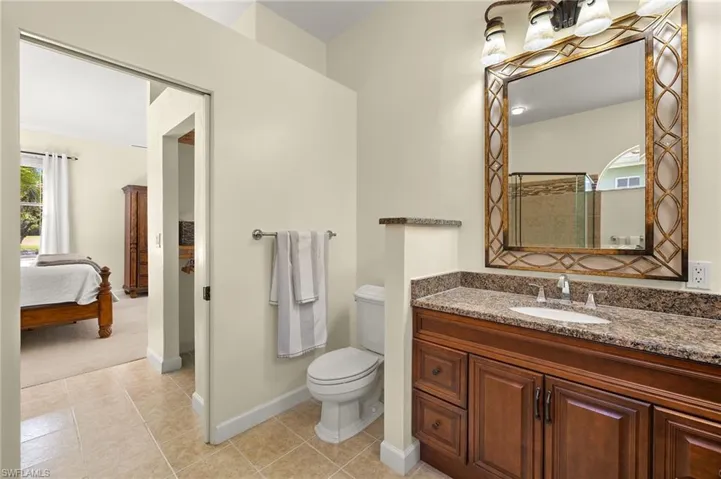 Ensuite bathroom with vanity, light tile patterned floors, and a shower