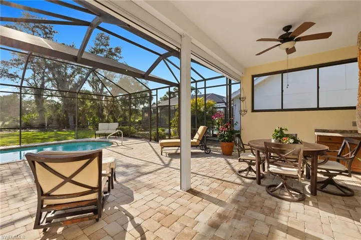View of patio with a lanai, an outdoor pool, outdoor dining area, and a ceiling fan