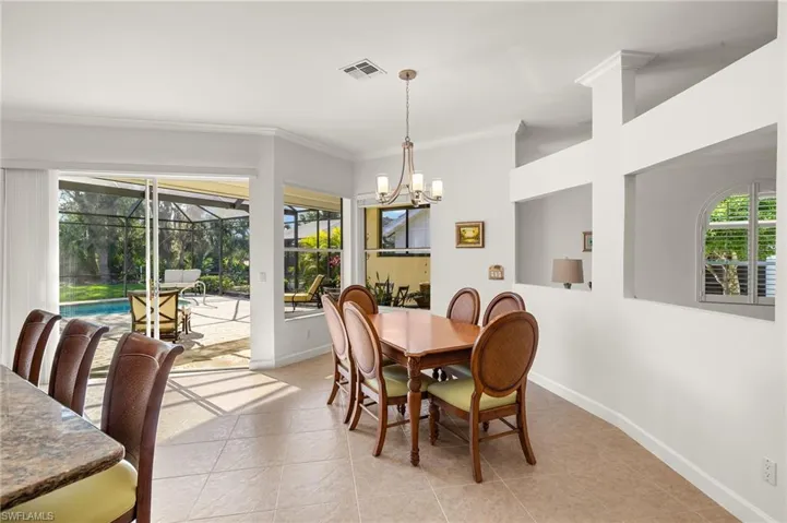Dining area with crown molding, a sunroom, light tile patterned floors, and a chandelier