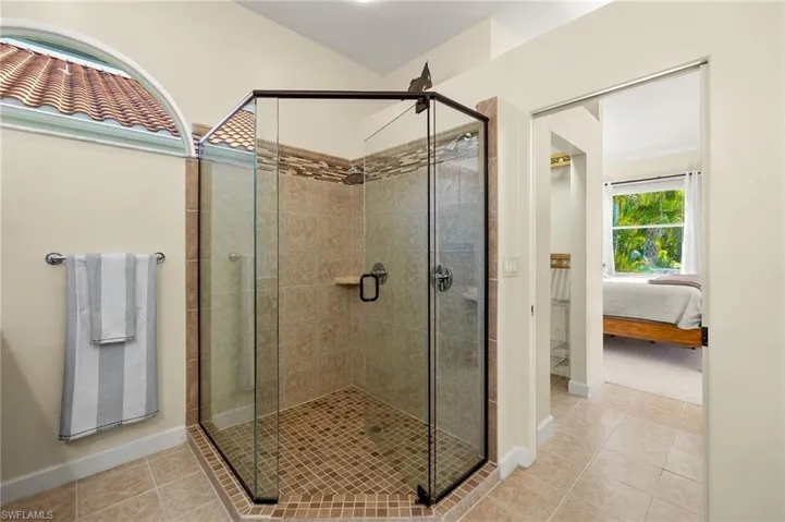 Ensuite bathroom featuring a shower stall and light tile patterned floors