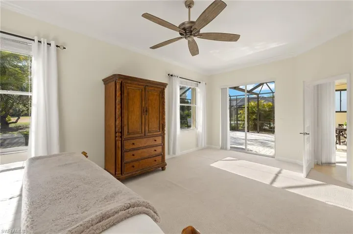 Bedroom with access to exterior, a sunroom, light carpet, ornamental molding, and a ceiling fan