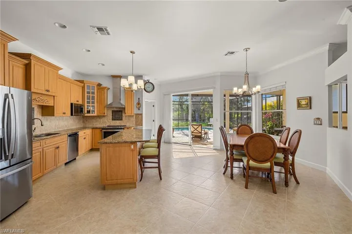 Kitchen with a chandelier, dark stone countertops, glass insert cabinets, stainless steel appliances, and backsplash