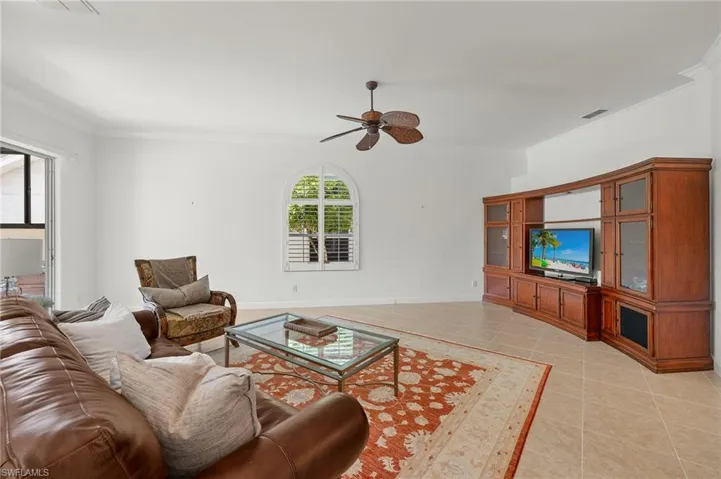 Living room with crown molding, light tile patterned floors, and a ceiling fan