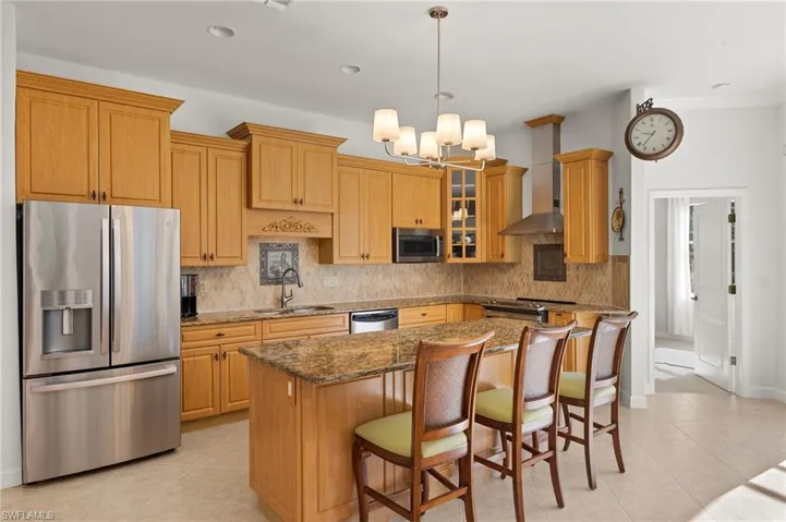 Kitchen with a kitchen bar, appliances with stainless steel finishes, dark stone counters, decorative backsplash, and recessed lighting