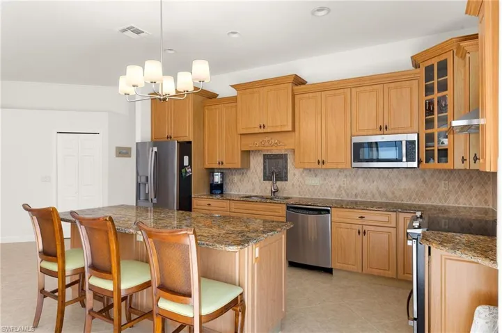 Kitchen with tasteful backsplash, a kitchen breakfast bar, stainless steel appliances, a center island, and hanging light fixtures
