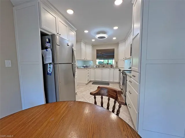 Beautifully updated eat-in kitchen with stainless steel appliances, white cabinets, light stone counters, and recessed lighting