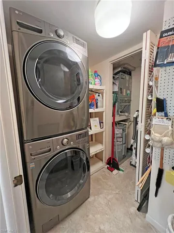In-unit laundry area featuring stacked washing machine and dryer and storage space