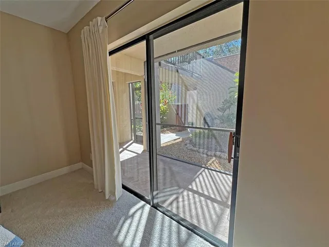 Roomy guest bedroom with queen bed and sliders to courtyard