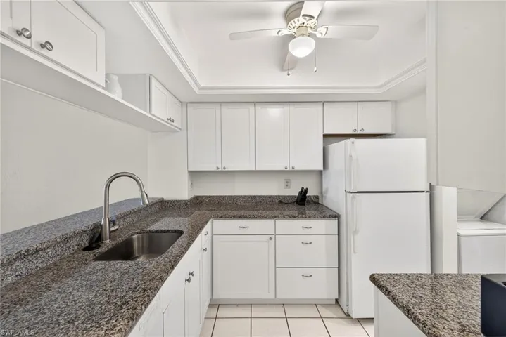 Kitchen with freestanding refrigerator, white cabinets, and light tile patterned flooring