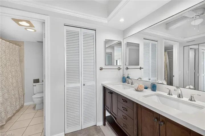 Bathroom featuring a closet, double vanity, light tile patterned flooring, recessed lighting, and ornamental molding