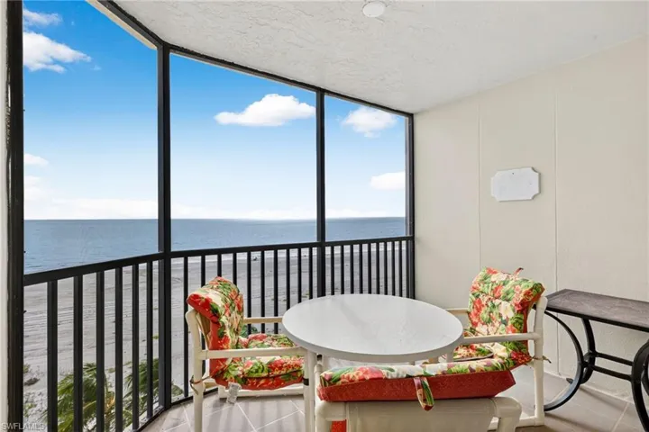 Sunroom with expansive windows, a water view, tile patterned floors, and a textured ceiling