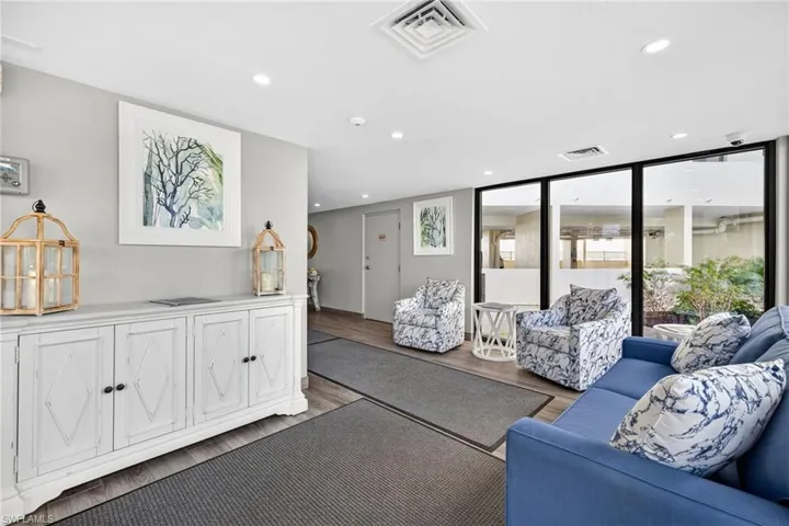 Living room with wood finished floors, recessed lighting, and a wall of windows