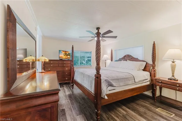 Master bedroom with dark wood finished floors, a ceiling fan, and ornamental molding