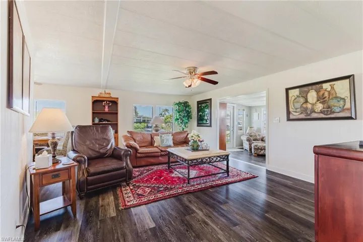 Living area with dark wood-style floors, wooden walls, and a ceiling fan