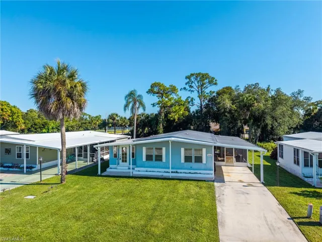View of front of house with a front yard, driveway, a carport, and a sunroom