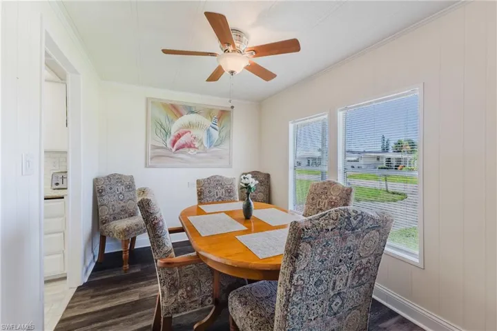 Dining space with crown molding, dark wood-type flooring, a ceiling fan, and wooden walls