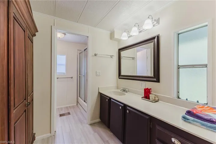 Bathroom with vanity, a shower stall, crown molding, and light wood finished floors