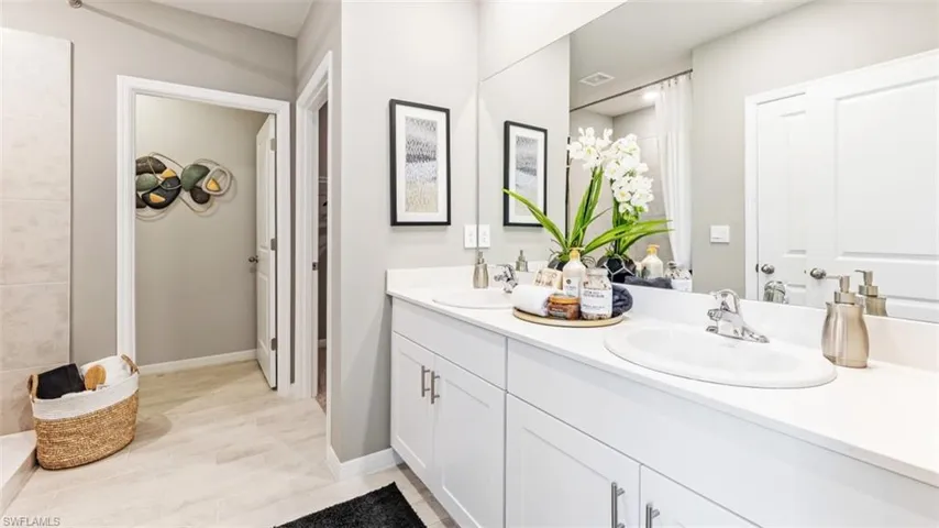 Model home. Full bathroom featuring double vanity and baseboards