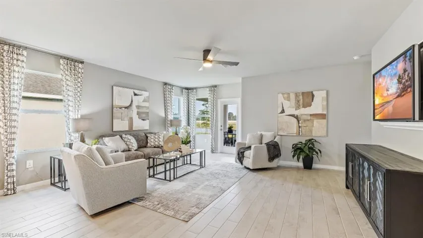 Model home. Living room with a ceiling fan and light wood-style flooring