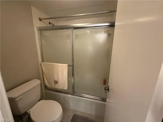 Bathroom featuring combined bath / shower with glass door and light tile patterned flooring
