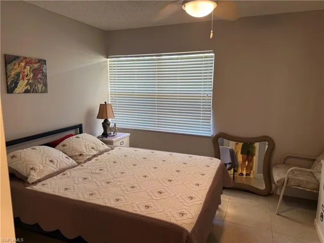 Bedroom with a textured ceiling, ceiling fan, and light tile patterned flooring