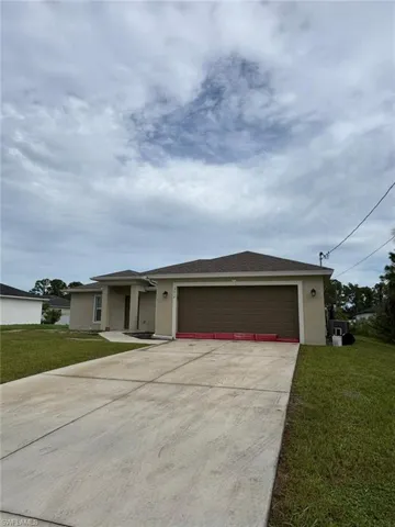Ranch-style house featuring stucco siding, a front yard, driveway, and a shingled roof