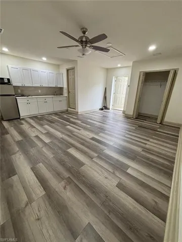 Unfurnished living room with recessed lighting, light wood-style flooring, ceiling fan, and attic access