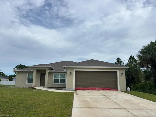 View of front facade with stucco siding, a shingled roof, and concrete driveway