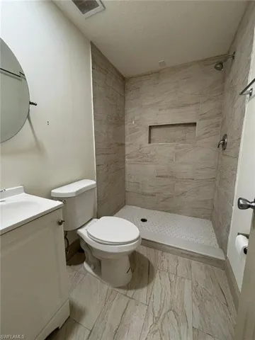 Full bath featuring vanity, a shower stall, and a textured ceiling