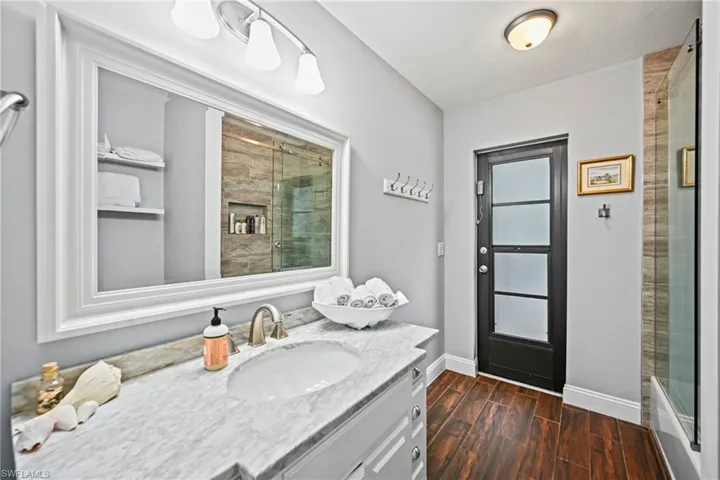 Full bath with pool access featuring wood tiled floors, vanity, and tiled shower / bath combo