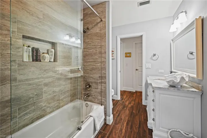 Full Bath with Pool access, with vanity, dark wood-type flooring, and bathtub / shower combination