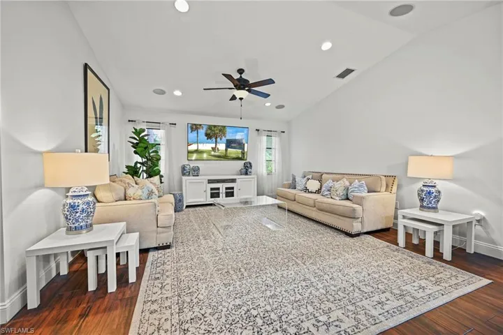 Living room with dark wood-style floors, vaulted ceiling, recessed lighting, and a ceiling fan