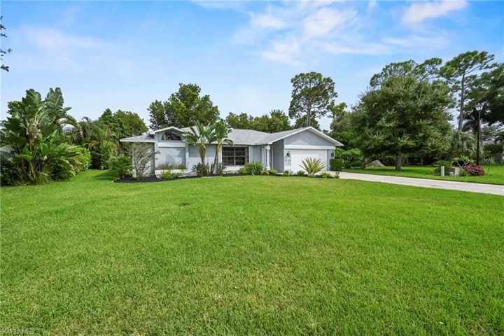 View of front of home with a front yard, driveway, a garage, and view of wooded area