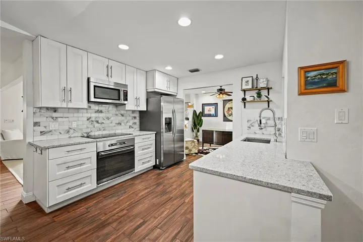 Kitchen with light stone counters, white cabinetry, tasteful backsplash, appliances with stainless steel finishes, and recessed lighting
