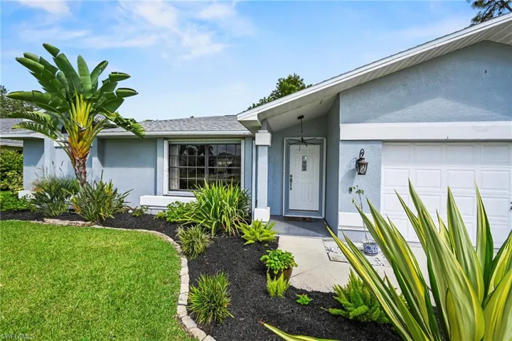 Doorway to property featuring stucco siding, an attached garage, and a lawn