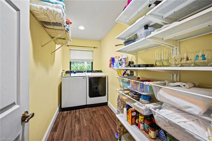 Laundry area featuring dark wood-style flooring, washer and clothes dryer, recessed lighting & lots of storage