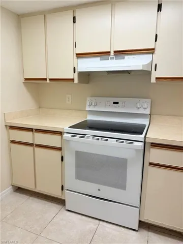 Kitchen with white range with electric cooktop and light tile patterned floors