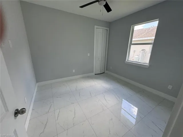 Tiled spare room featuring ceiling fan