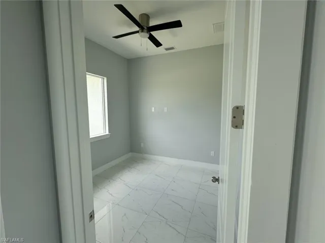 Empty room featuring light tile patterned flooring and ceiling fan