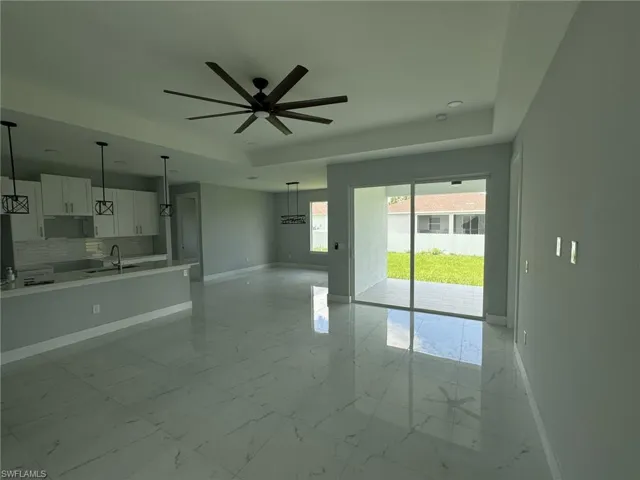Unfurnished living room featuring light tile patterned flooring, sink, and a tray ceiling