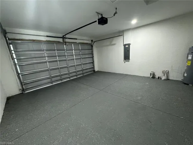 Garage with a garage door opener, water heater, and electric panel