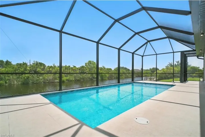 Outdoor pool with a sunroom, a lanai, a water view, and a patio area