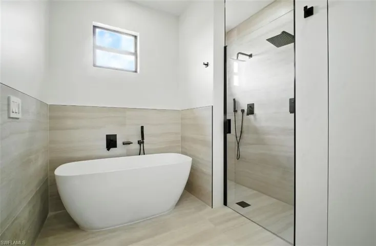 Full bath featuring a shower stall, a soaking tub, and tile walls
