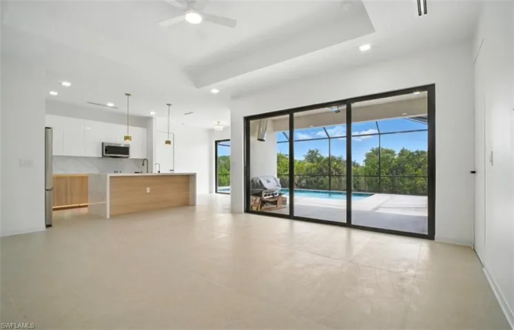 Unfurnished living room featuring a ceiling fan, a sunroom, a tray ceiling, concrete floors, and recessed lighting