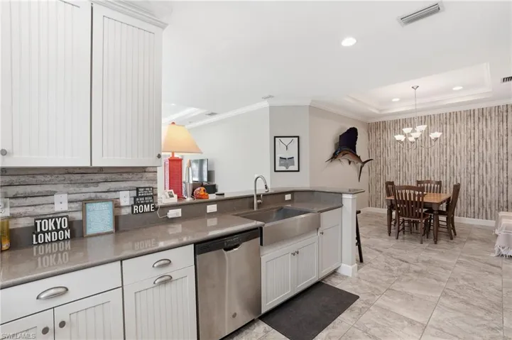 Kitchen featuring white beadboard cabinetry, stainless steel appliances, a farmhouse sink, and light-toned countertops