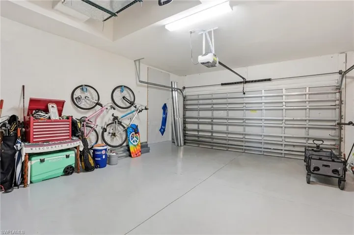 Spacious garage featuring a light gray epoxy floor coating, white painted walls, and a visible garage door opener mechanism