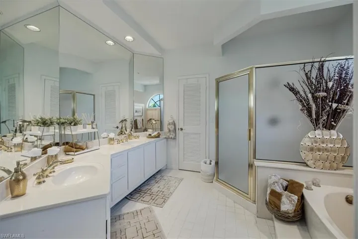 Bathroom featuring a stall shower, double vanity, a garden tub, a closet, and recessed lighting
